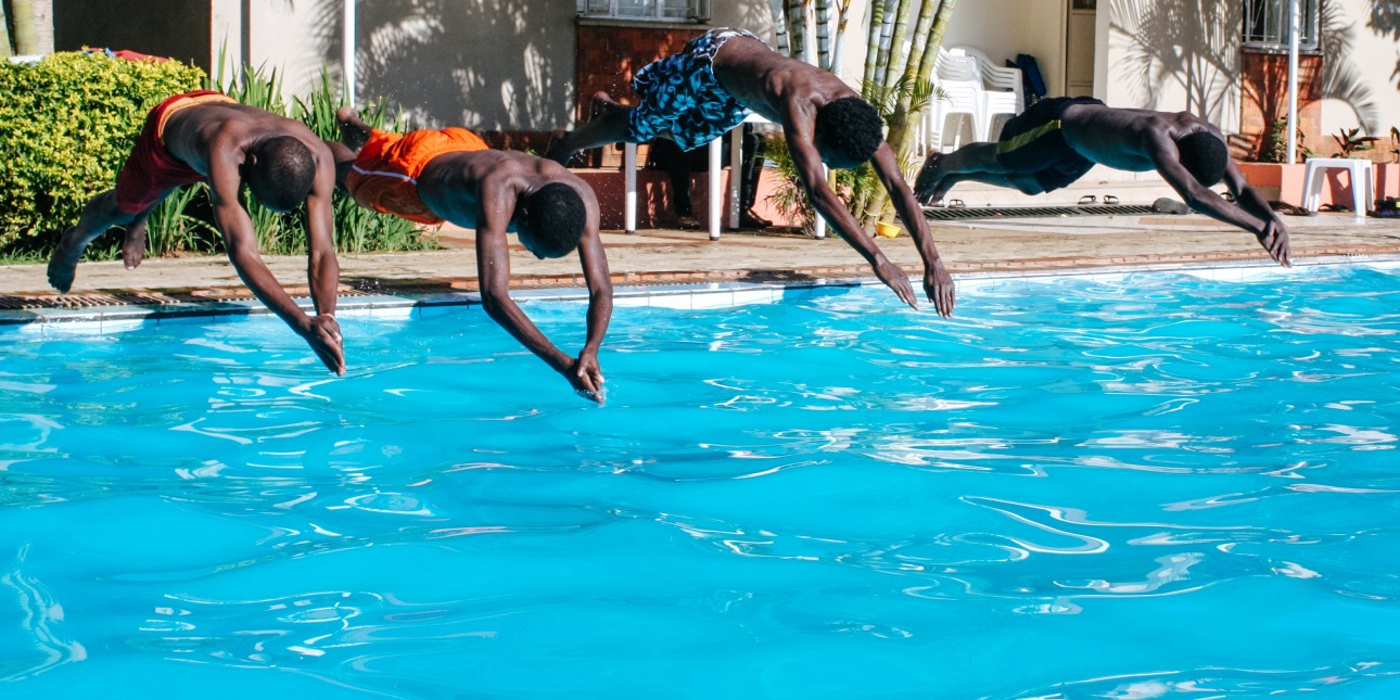 4 boys jumping into a pool