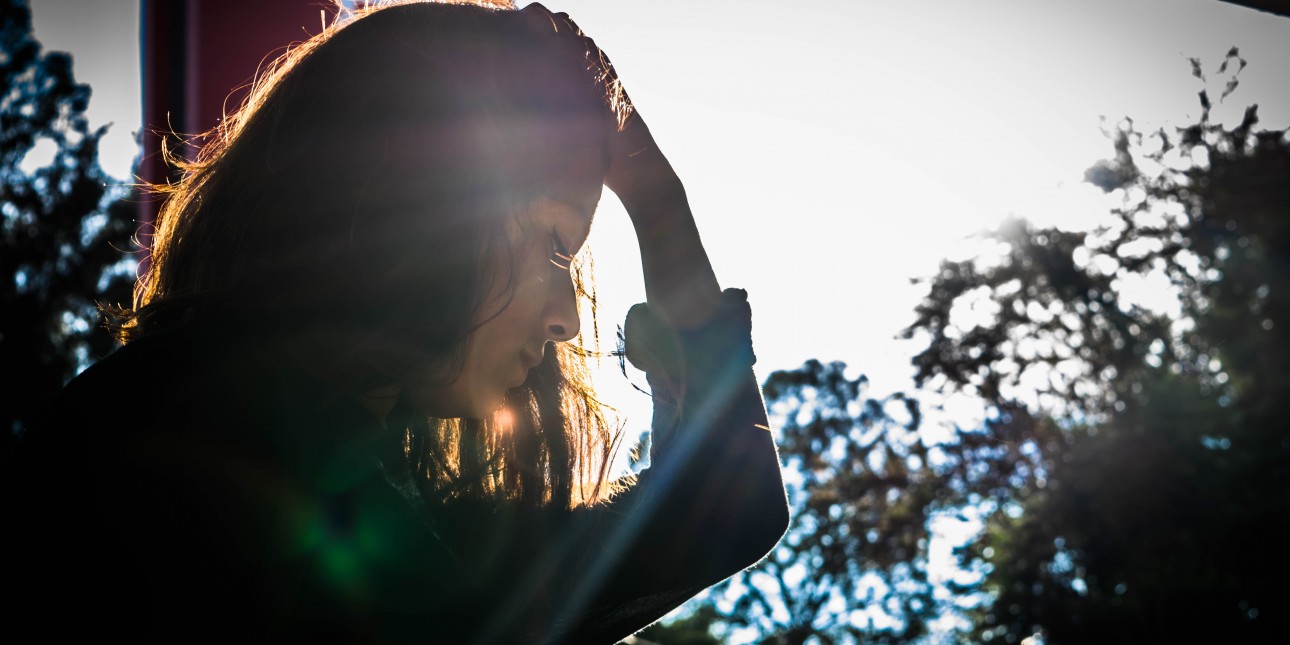 Person looking down standing in sunset