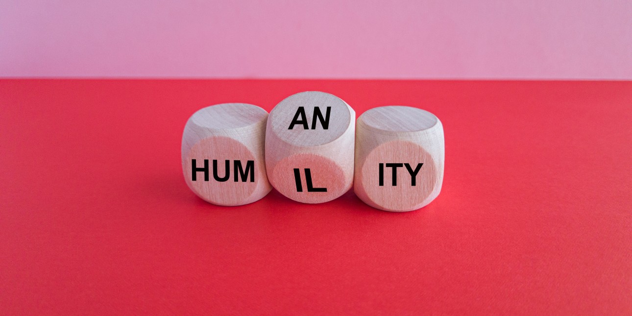 Wooden dice that read hum(an/il)ity.