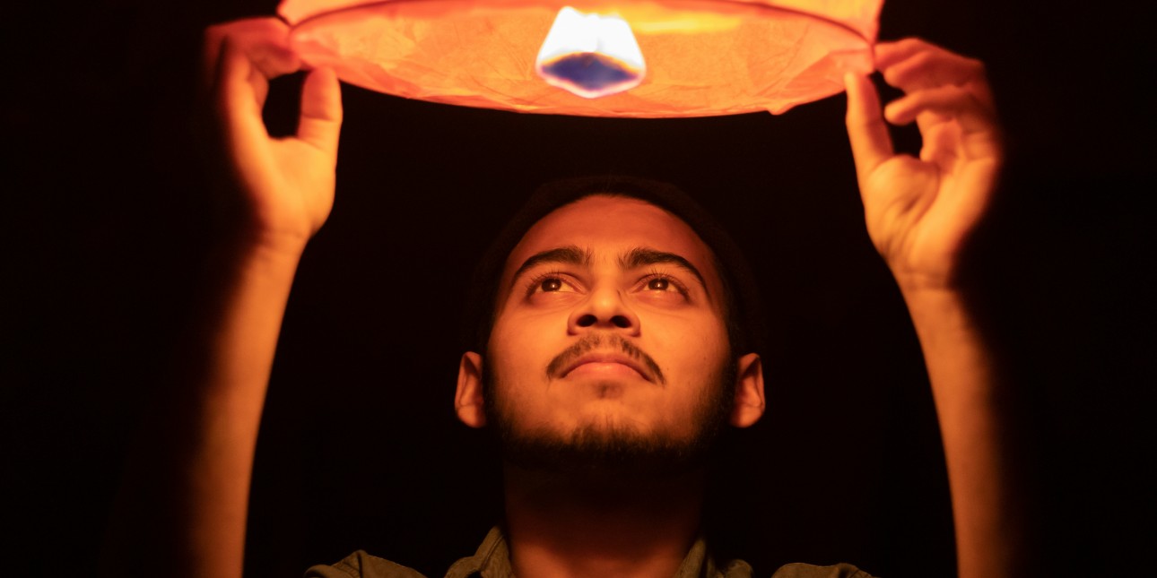 a young man holding a sky lantern