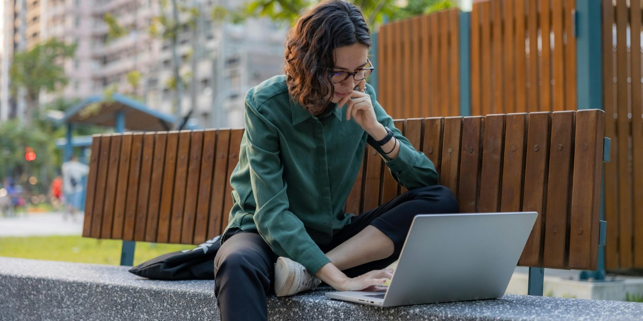 A woman using a laptop at a park.