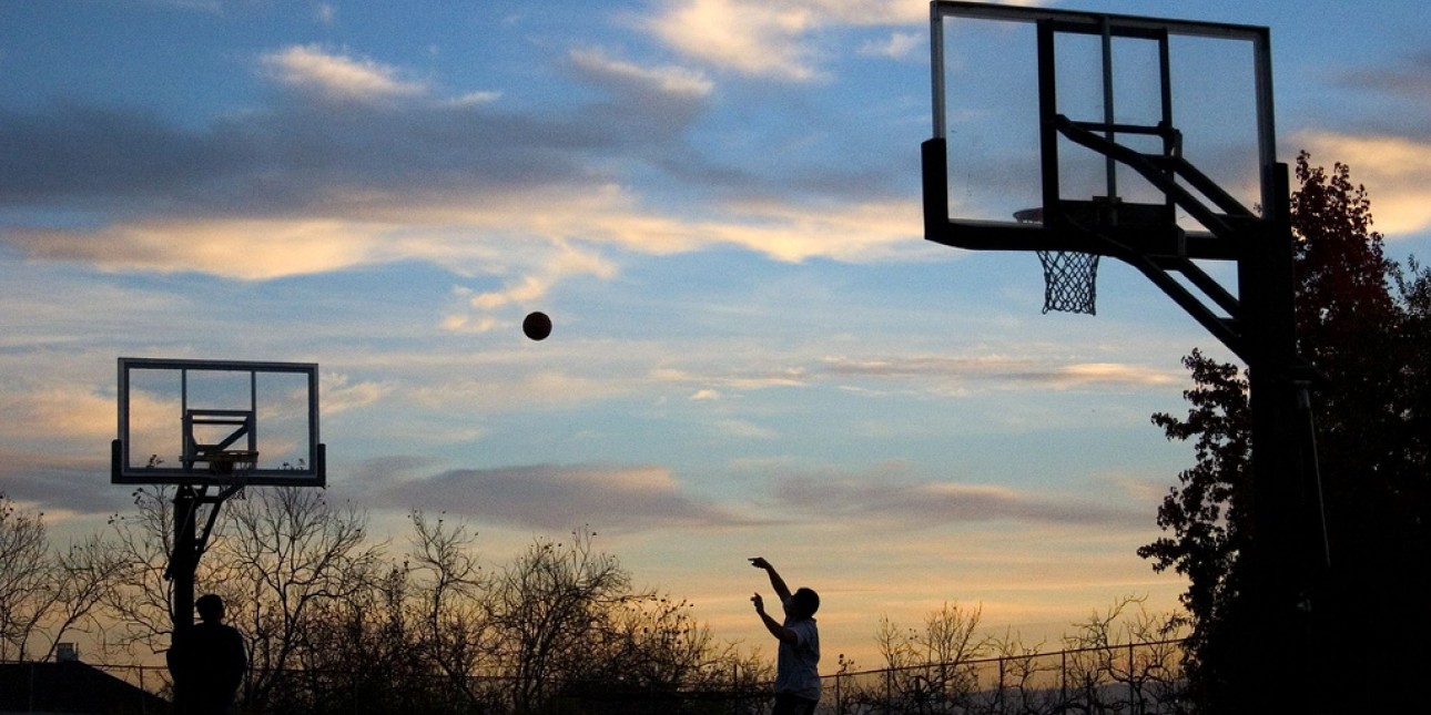 person playing basketball at sunset
