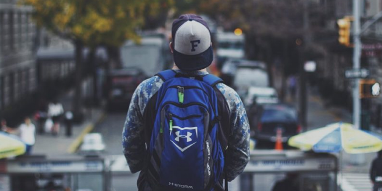 Young man wearing a backpack looking at city