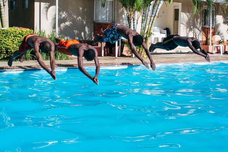 4 boys jumping into a pool