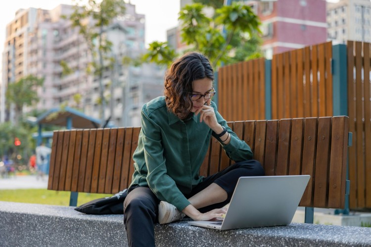 A woman using a laptop at a park.