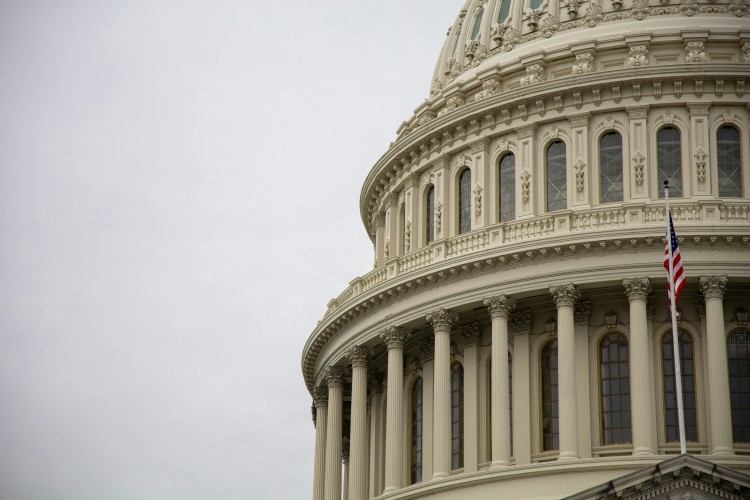 The Capitol dome and U.S. flag against the sky.