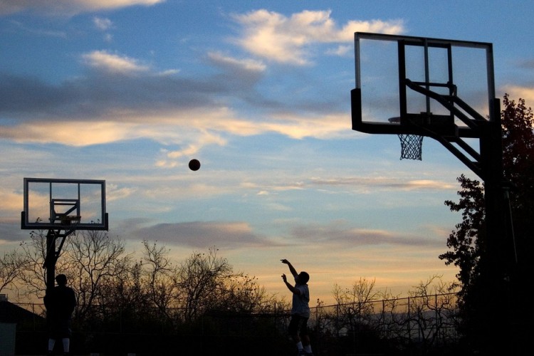 person playing basketball at sunset