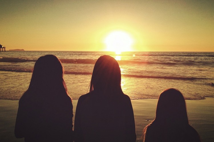 Three people staring at a sunset