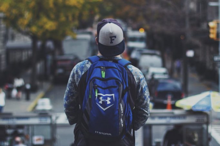Young man wearing a backpack looking at city